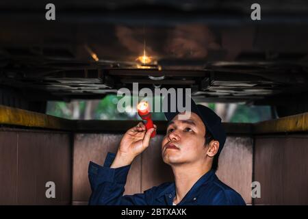male mechanic holding and shining flashlight to checking under a car problem Stock Photo
