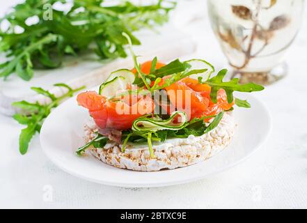 Open sandwich with  crispbread salted salmon, cream cheese, sliced cucumber and arugula on plate. Stock Photo