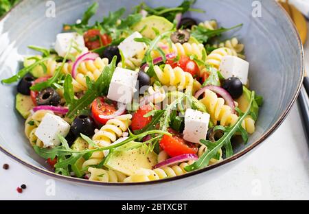 Pasta salad with tomato, avocado, black olives, red onions and cheese feta. Mediterranean cuisine. Stock Photo