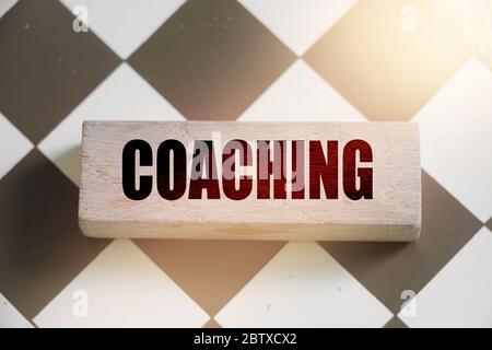 Coaching word on a wooden block put on chess board. Mentorship consulting personal achievements in career and business concept Stock Photo