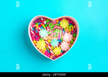 mix colorful chocolate sweets lie in gift box shape of heart on colorful background Flat lay Top view Stock Photo