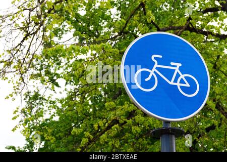 Sustainable transport. Blue road sign or signal of bicycle lane with green trees and nature background