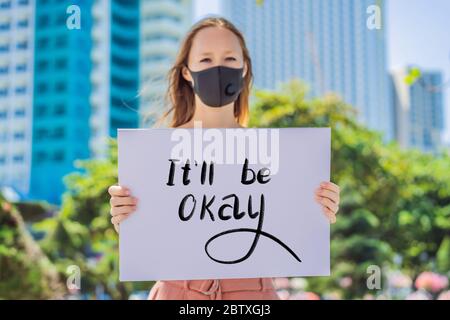 woman in medical mask prevents coronavirus disease holds a poster Everything Will Be Ok Hand written text - lettering isolated on white. Coronovirus Stock Photo