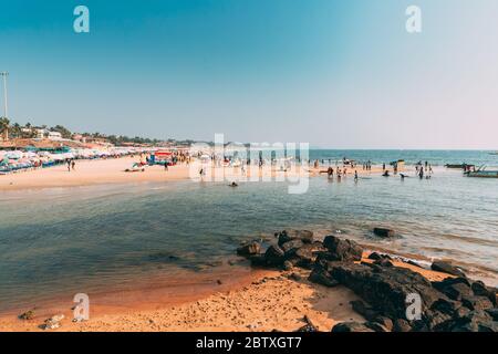 Mapusa, Anjuna, Goa, India - February 19, 2020: People Visit And Relax On Baga Beach At Sunny Evening Under Blue Sky. Stock Photo