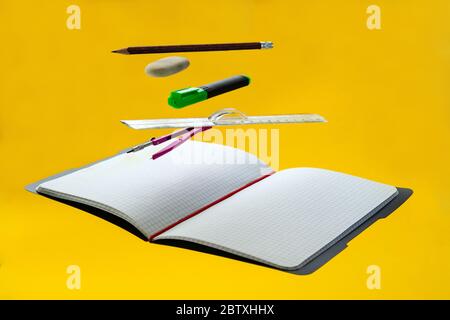 Levitating school supplies for math - notebook, pen, ruler, pencil, divider and eraser on yellow background. Concept of education and creativity Stock Photo
