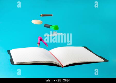 Levitating school supplies for math - notebook, pen, ruler, pencil, divider and eraser on blue background. Concept of education and creativity Stock Photo