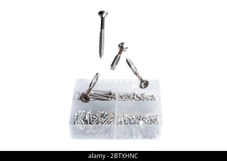 Metal screws levitating above plastic screw box isolated on white background. Manufacturing for construction industry Stock Photo