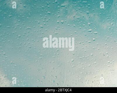 Wet window with rain drops and a cloudy sky outside background. Stock Photo