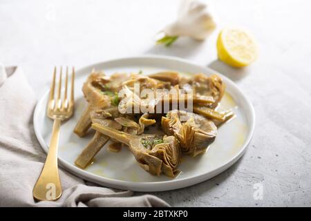 Cooked Italian Artichokes on the white plate with lemon Stock Photo