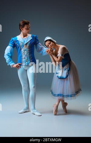 Young and graceful ballet dancers as Cindrella fairytail characters on studio background. Art, motion, action, flexibility, inspiration concept. Flexible caucasian ballet dancers in inspired dancing. Stock Photo