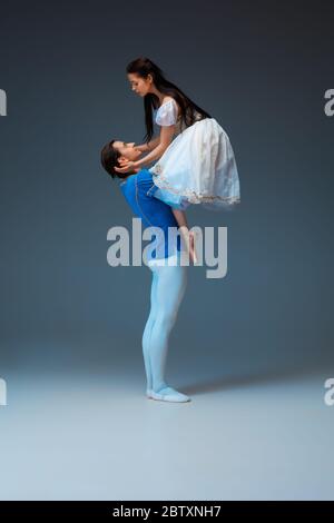 Young and graceful ballet dancers as Cindrella fairytail characters on studio background. Art, motion, action, flexibility, inspiration concept. Flexible caucasian ballet dancers in inspired dancing. Stock Photo