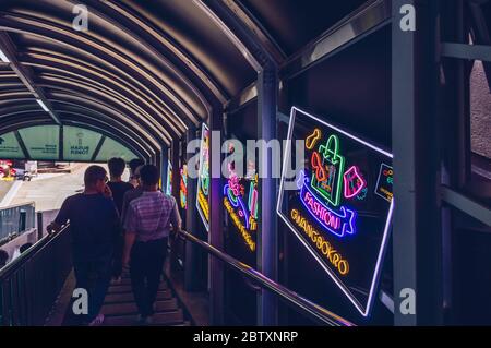 Busan, South Korea, September 14, 2019: people going down roofed staircase decorated with glowing neon banners neon Stock Photo