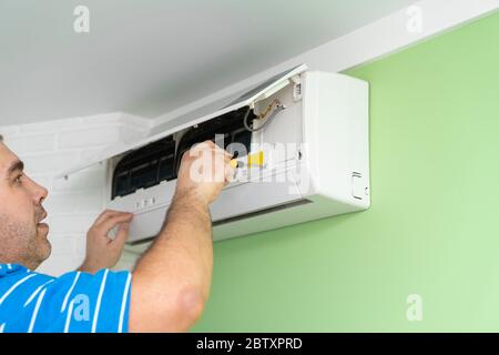 Male technician repairing and diagnosing air conditioners. Opening the cover and disassembling the housing Stock Photo