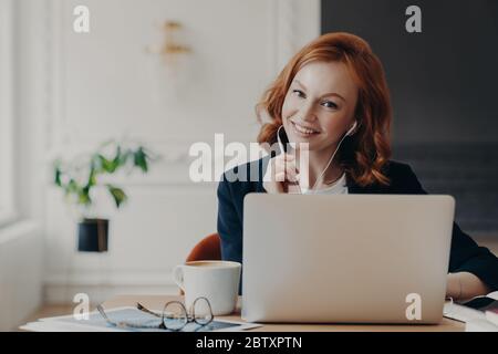 University student studies online from home, discusses project work with professor, poses in coworking space and drinks aromatic coffee. Video confere Stock Photo
