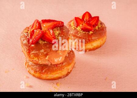 Three strawberry shortcake donut on a pink coloured background Stock Photo