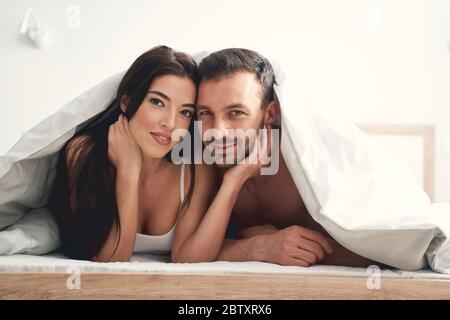 Newly wedded couple lying under the duvet Stock Photo