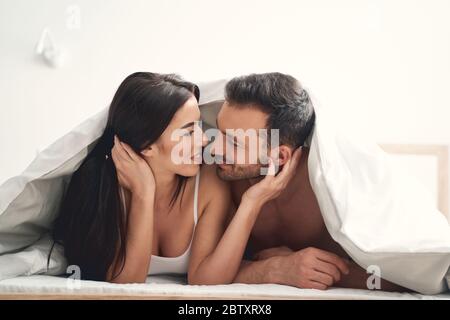 Happy married couple lying under the blanket Stock Photo