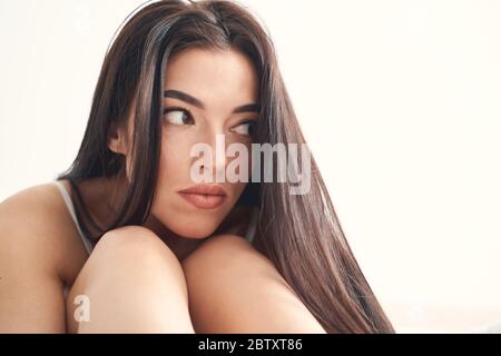 Depressed dark-haired Caucasian woman sitting all alone Stock Photo