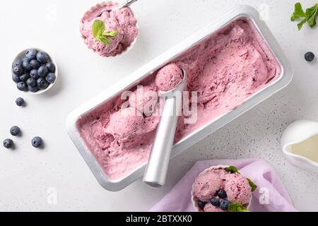 Blueberry homemade ice cream in metallic tub on white background. View from above. Clean eating. Without sugar. Stock Photo