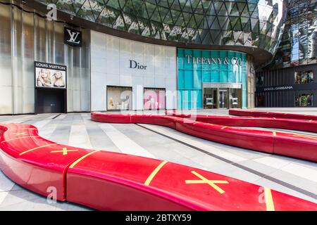 Long red bench seatings with a cross of no sitting to indicate safe distancing measure at ION shopping centre Stock Photo