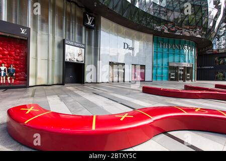 Long red bench seatings with a cross of no sitting to indicate safe distancing measure at ION shopping centre Stock Photo