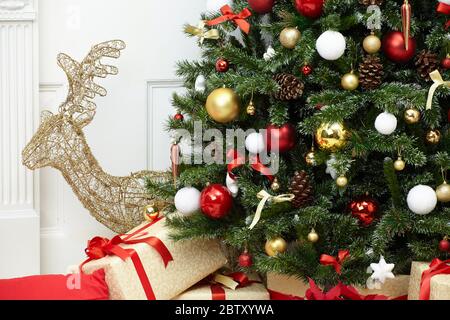 Fragment of a beautiful Christmas tree in home with colorful decorations, cones, balls, ribbons and gifts Stock Photo
