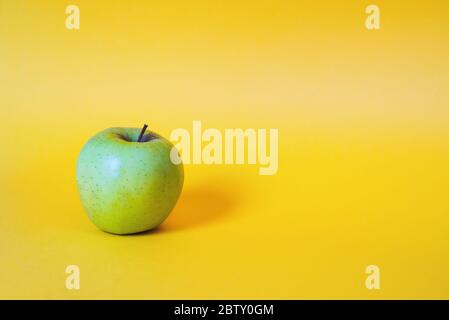 Single apple on yellow background Stock Photo