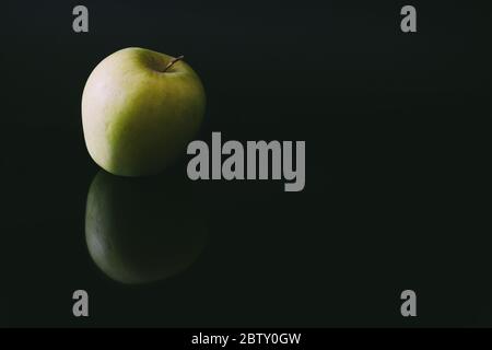Single apple reflected on black background Stock Photo