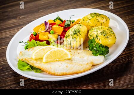 Fish dish - fried fish fillets with boiled potatoes and grilled vegetables Stock Photo