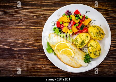 Fish dish - fried fish fillets with boiled potatoes and grilled vegetables Stock Photo