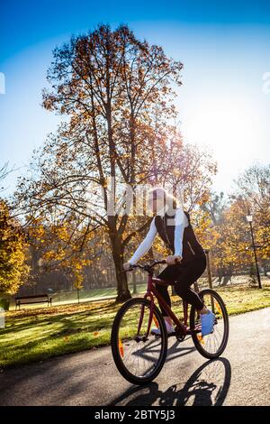 Urban biking - woman riding bike in city park Stock Photo