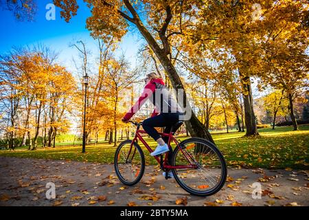 Urban biking - woman riding bike in city park Stock Photo