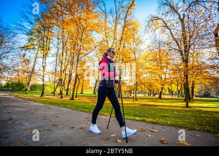 Nordic walking - middle-age woman working out in city park Stock Photo