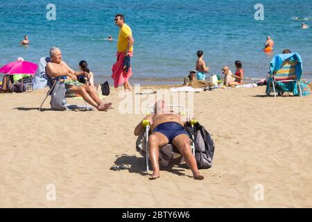 Las Palmas, Gran Canaria, Canary Islands, Spain. 28th May, 2020.  Locals basking on the city beach in Las Palmas on Gran Canaria as The Canary Islands, and many other regions of Spain, enjoy the lifting of restrictions during phase 2 of lockdown easing. With 40% of the Canary slands population dependent on tourism for employment, it was a relief for many to hear that tourists will be allowed to visit spain, without quarantine, from July. Alan Dawson/Alamy Live News. Stock Photo