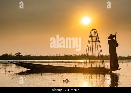 Fisherman at Inle Lake with traditional Intha conical net at sunset, fishing net, leg rowing style, Intha people, Inle Lake, Shan state, Myanmar (Burm Stock Photo