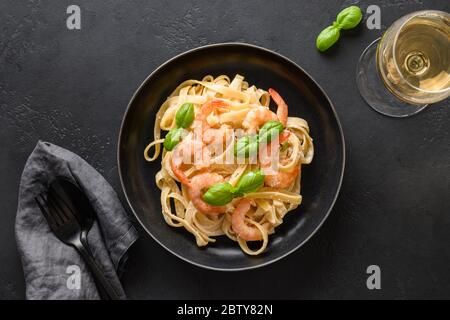 Italian fettuccine with shrimps, seafood served wine glass on black table. View from above. Stock Photo