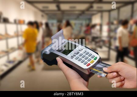 hand using credit card swiping machine to pay. Hand with credit card swipe through terminal for payment Stock Photo