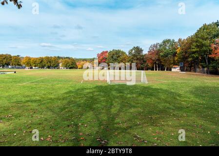 Empty football pitch with goals surrounded by colourful trees in a park during the autumn colours season Stock Photo