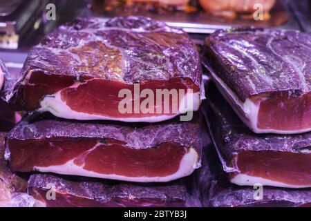 Many homemade German mix of meat specialties, speck ham sausages pile or stack on counter top, for sale, during food festival, outdoor outside marketp Stock Photo