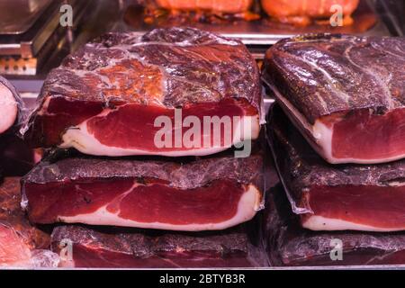 Many homemade German mix of meat specialties, speck ham sausages pile or stack on counter top, for sale, during food festival, outdoor outside marketp Stock Photo