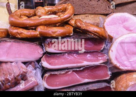 Many homemade German mix of meat specialties, speck ham sausages pile or stack on counter top, for sale, during food festival, outdoor outside marketp Stock Photo