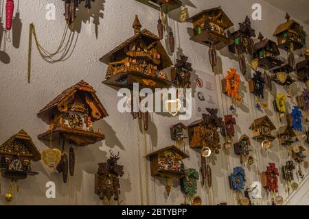 Many wooden classic carved clocks hanging on the wall, in the store. Stock Photo