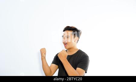Asian man raising his hand on the right side celebrated and saying yes. Competition winning concept Stock Photo
