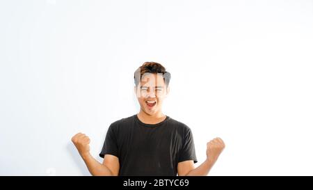 Portrait of a satisfied young asian man celebrating success isolated over white background Stock Photo