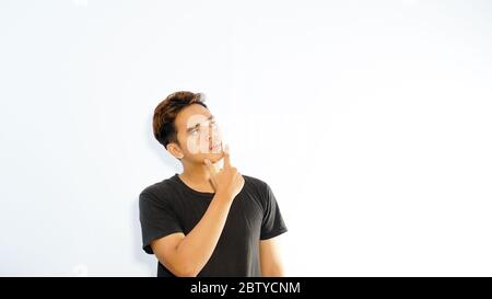 A portrait of a young asian man thinking looking up isolated over white background Stock Photo