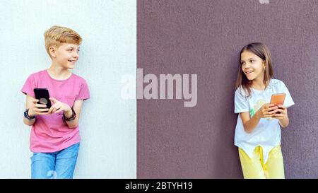 Trendy kids using mobile phones while keeping social distance Stock Photo