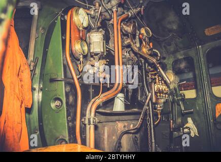 Atmospheric, close up of train driver controls inside vintage UK steam locomotive cab at night. Driving vintage trains. Stock Photo