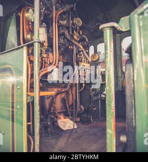 Close up of train driver controls, on footplate inside vintage UK steam locomotive cab in evening winter sunshine. Driving vintage trains. Stock Photo