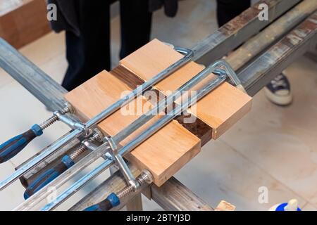 Three Wooden Bars are Glued to Each Other at Woodwork. Wood Pieces Fixed by Jaws Vise Tongs. Stock Photo