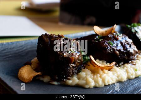 Ossobuco or osso buco is a specialty of Lombard cuisine of cross-cut veal shanks braised with vegetables, white wine and broth. Served with either ris Stock Photo